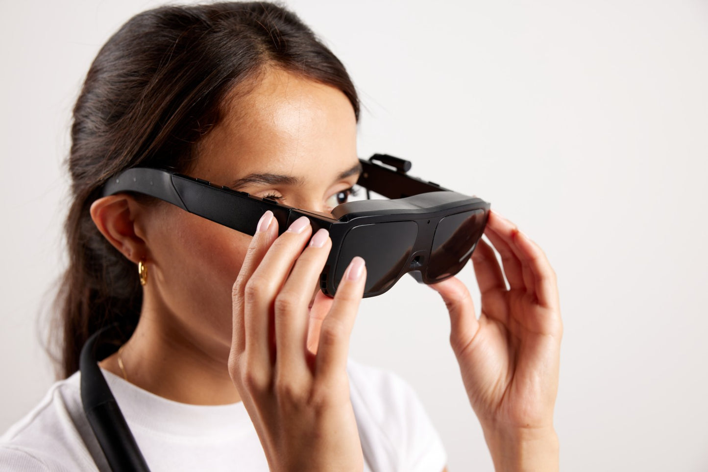 A woman wearing black electronic glasses retaining her vision back.