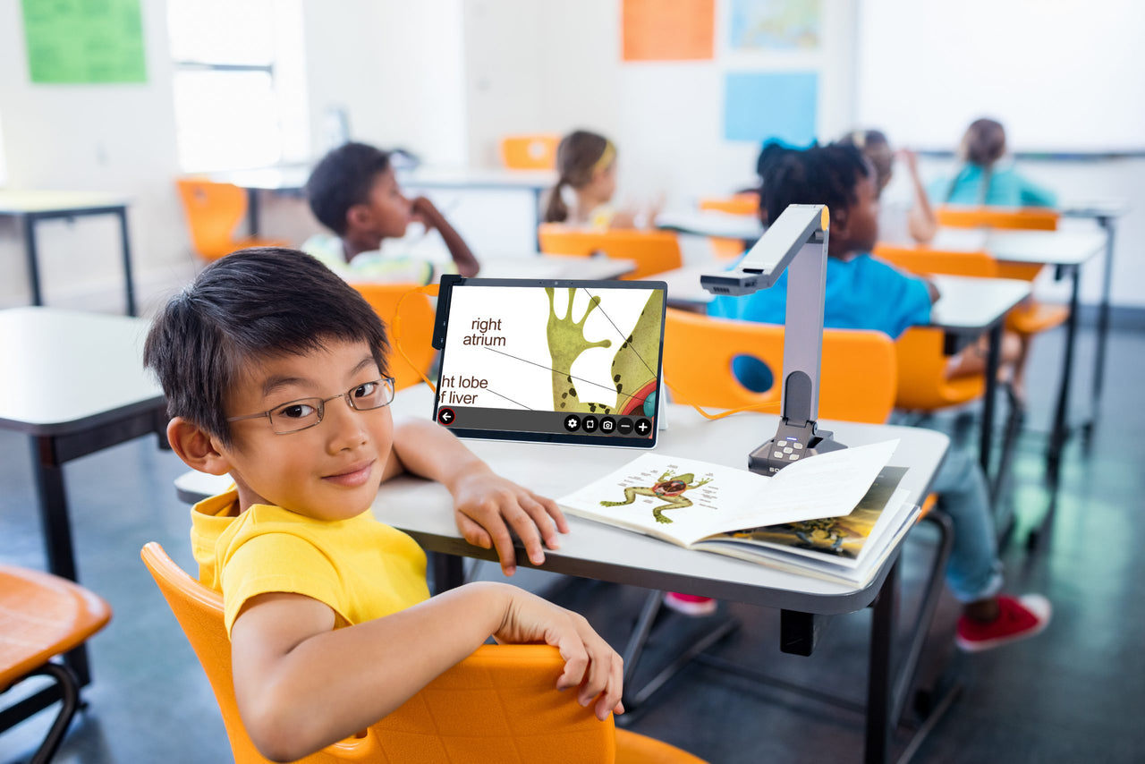 A young boy in a classroom using a ProdigiSoft assistive device on a tablet to magnify and read educational material about anatomy.