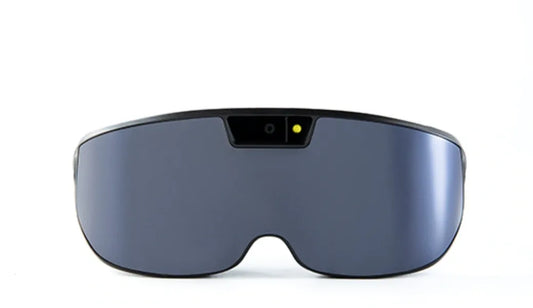 A pair of black electronic glasses with a yellow light on the bridge. The glasses have a modern, sleek design and are designed to help people with low vision.