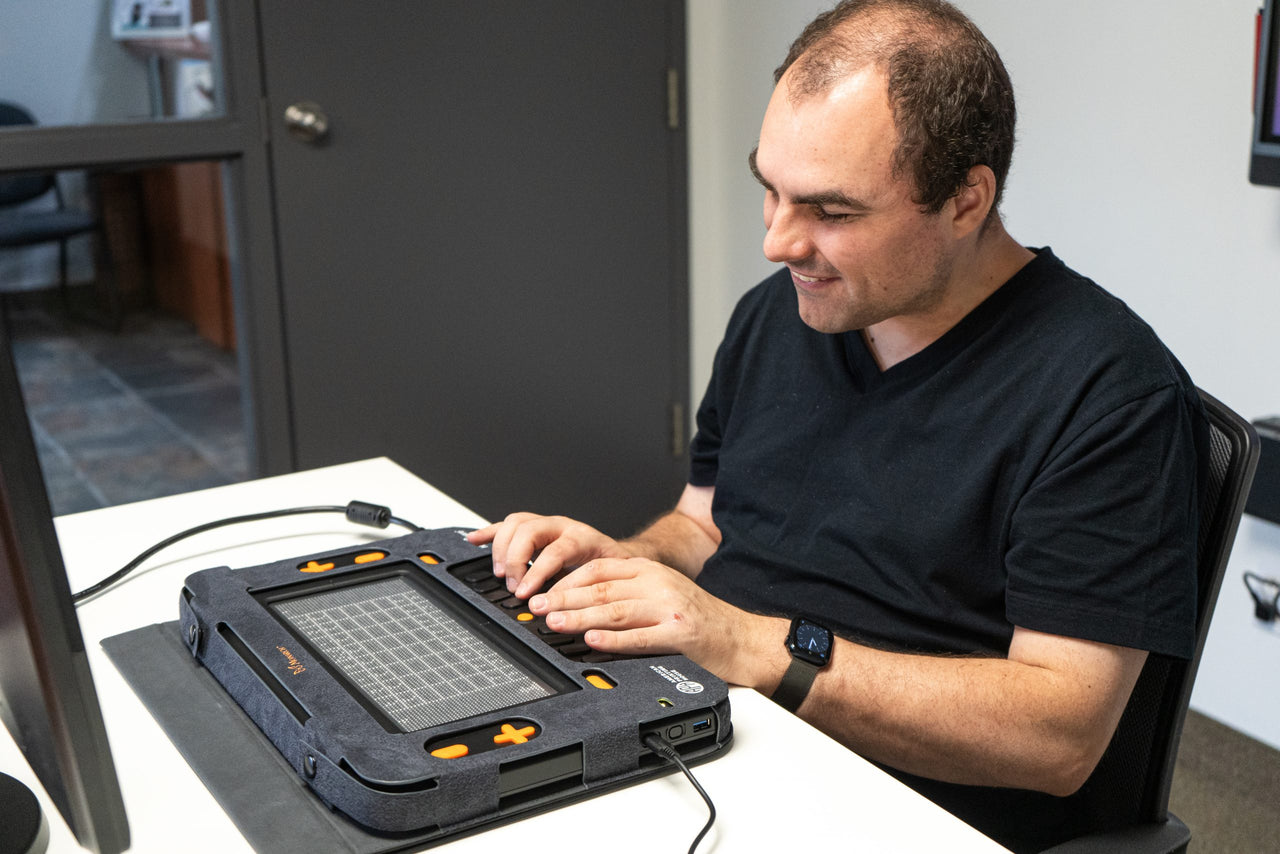 Man using a Monarch Braille Display for tactile reading. The Monarch tablet supports accessible learning for visually impaired users.