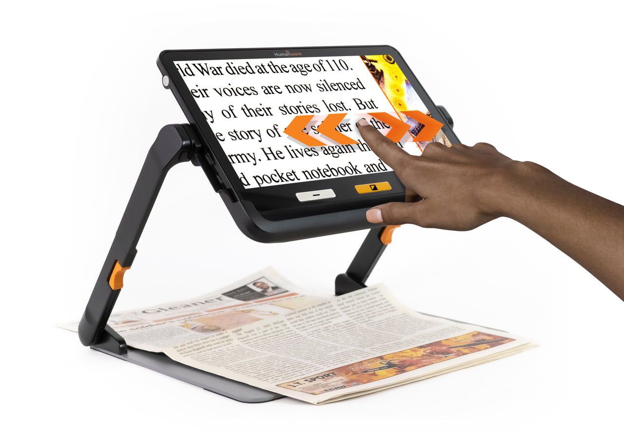 A hand is shown swiping across the screen of a Humanware Explore 12 portable video magnifier, which is magnifying a newspaper.