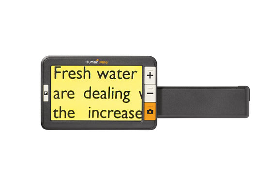 A handheld low vision reading device with a magnified display showing text about climate change. The device has a Humanware logo and controls for zooming and taking photos.